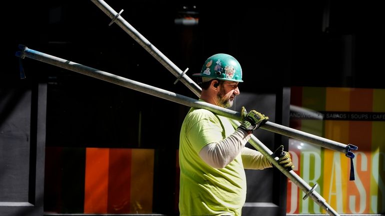 A construction worker carries scaffolding parts on March 14, 2024,...