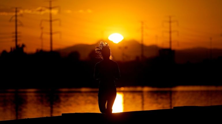 A runner jogs along Tempe Town Lake at sunrise, Wednesday,...