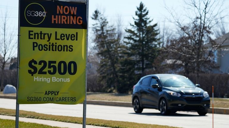 File - A hiring sign is shown in Wheeling, Ill.,...