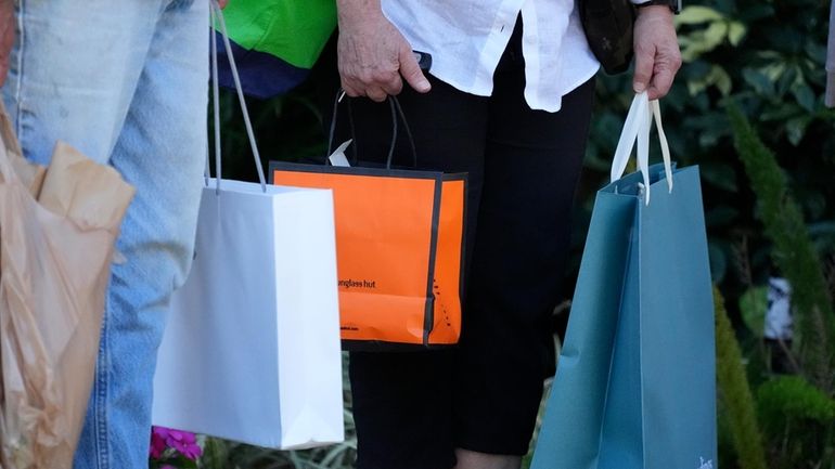 Shoppers carry bags after making purchases in Bradenton, Fla., Feb....