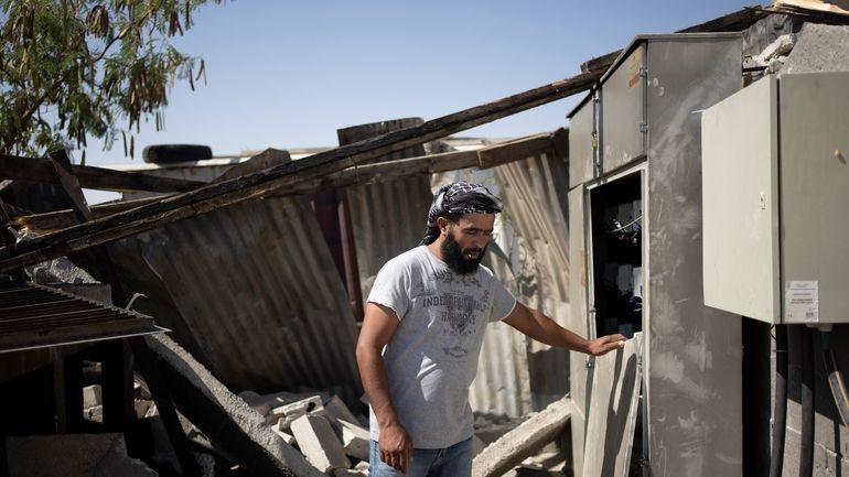 Bilal Hathaleen stands in the rubble of equipment providing electricity...