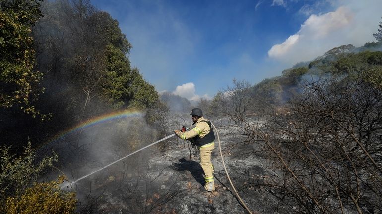 An Israeli firefighter works to extinguish a fire after a...