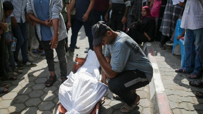 Palestinians mourn over the bodies of relatives killed in an...