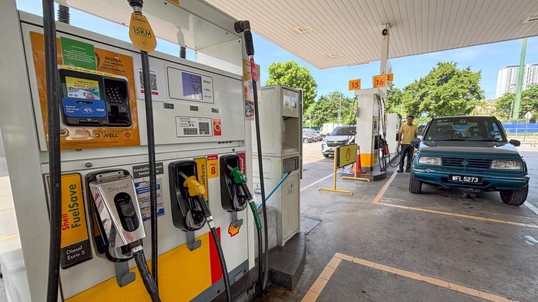 A car owner pumps at a petrol station in Kuala...