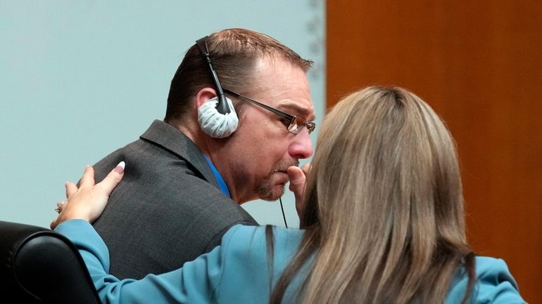 Defense attorney Mariell Lehman puts her arm on James Crumbley...