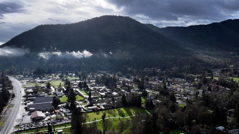 A vehicle at left drives down Rogue River Highway as...