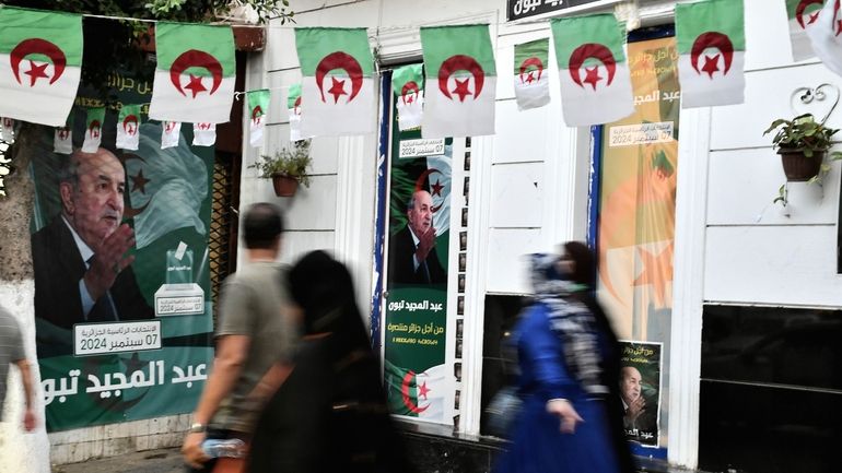 People walk past posters of Algerian President Abdelmadjid Tebboune, after...