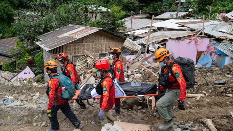 Rescuers carry a body from the landslide-hit village of Masara...