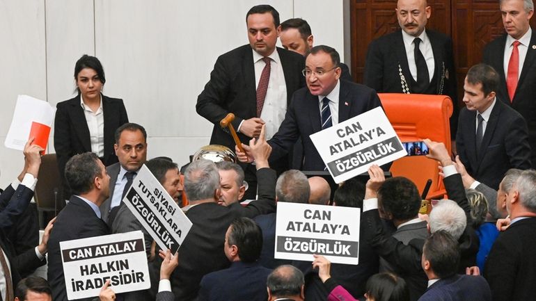 Turkish lawmakers, few holding up boards that read in Turkish:...