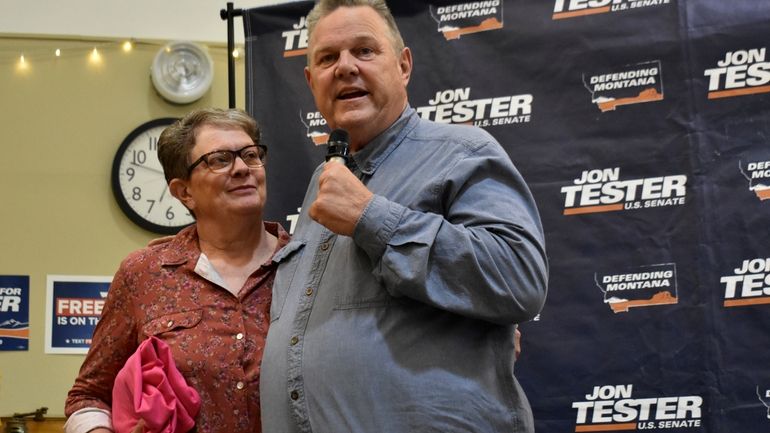 U.S. Sen. Jon Tester, D-Mont., speaks while standing next to...