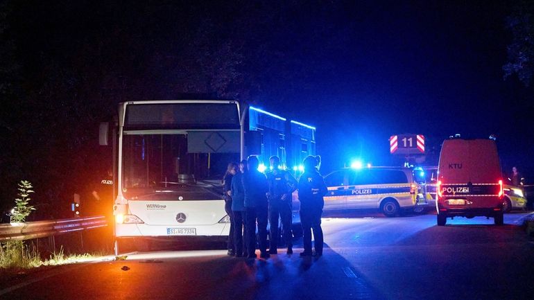 Police officers stand in front of a bus on a...