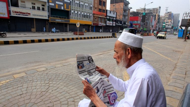 A man reads morning newspaper in a market, which closed...