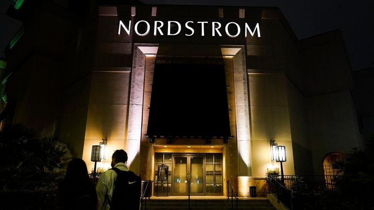 Two pedestrians walk near an entrance to a Nordstrom department...