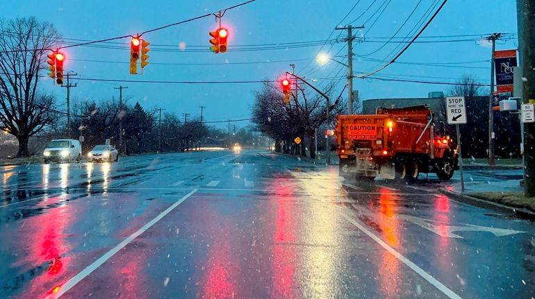 Precipitation falls and a salt spreader coats the roadway on...