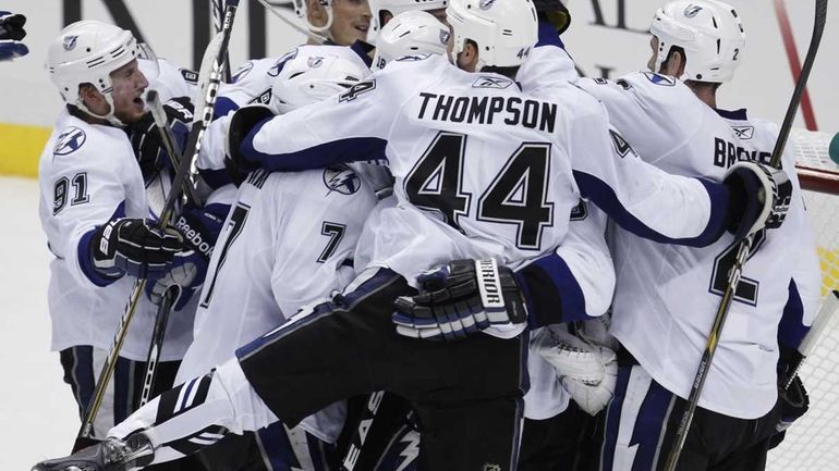 Tampa Bay Lightning players swarm goalie Dwayne Roloson to begin...