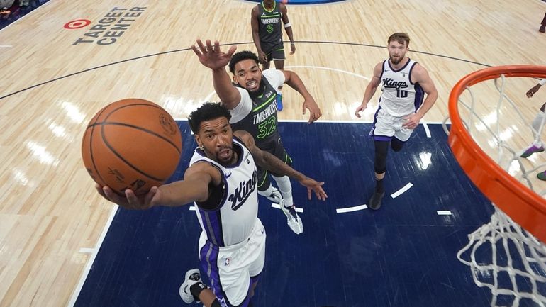 Sacramento Kings guard Malik Monk, front, shoots as Minnesota Timberwolves...