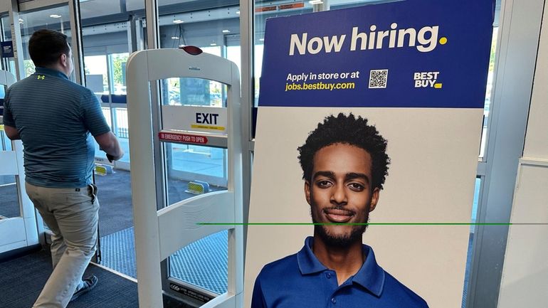 A hiring sign is displayed at a retail store in...