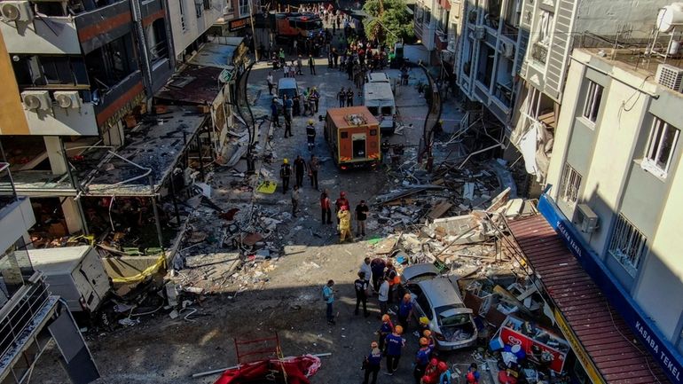 Firefighters and emergency team members work during the aftermath of...