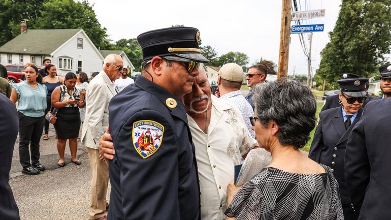 From left, East Brentwood Fire Commissioner Javier Valentin gets a hug...