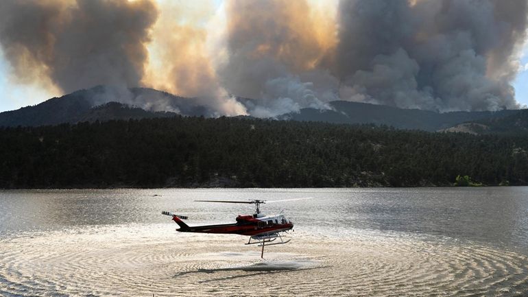 A helicopter collects water to drop on the Alexander Mountain...