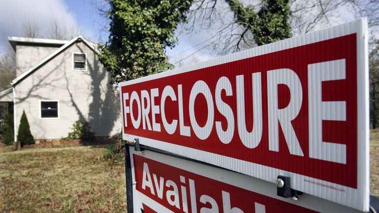 A foreclosure sign is seen on the lawn of a...