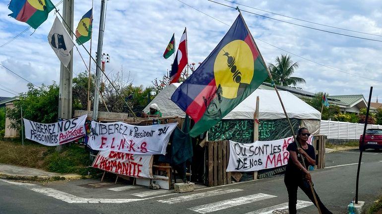 An indigenous Kanak holds the independent flag during the 171th...