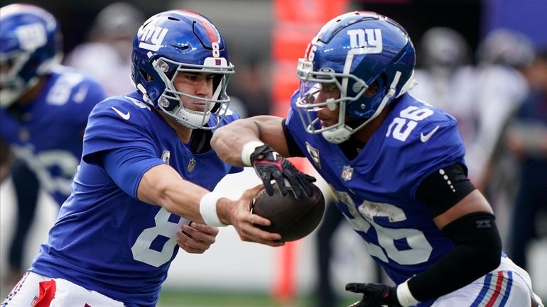 Giants quarterback Daniel Jones hands off the ball to Saquon Barkley...