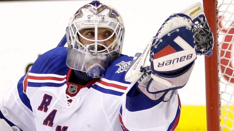 New York Rangers goalie Henrik Lundqvist gloves the puck while playing...