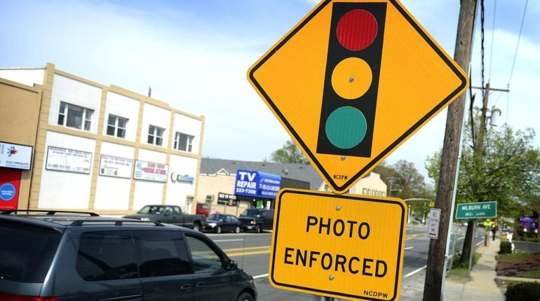 A red-light traffic camera sign at the intersection of Merrick...