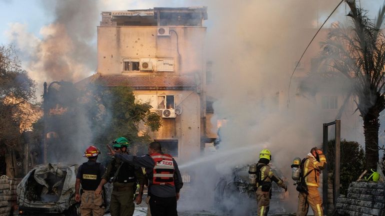 Israeli security and rescue forces work at the site hit...