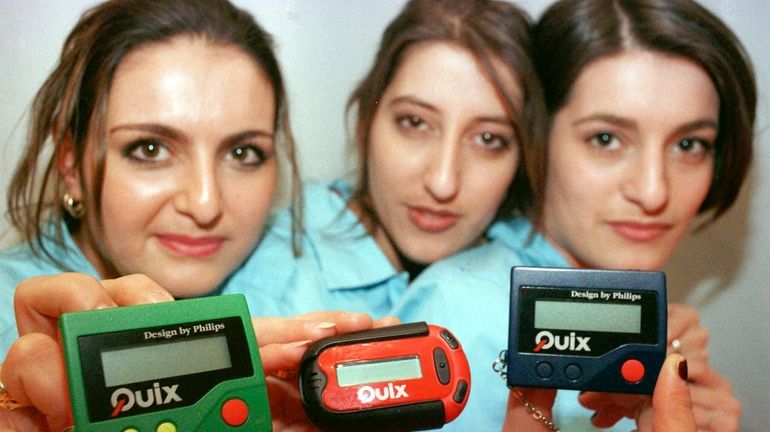 Three women hold the pager 'Quix' as they present it...