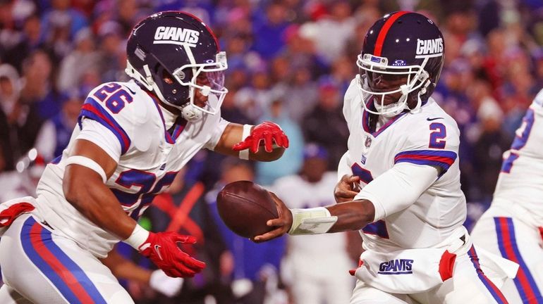 New York Giants quarterback Tyrod Taylor, center, hands off to...