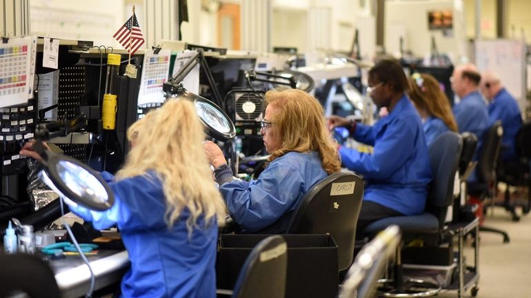 Workers at GE Aviation in Bohemia, on April 23. The unit is...