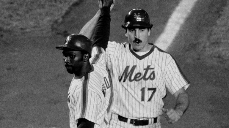 The Mets' Keith Hernandez high-fives Mookie Wilson as he crosses...