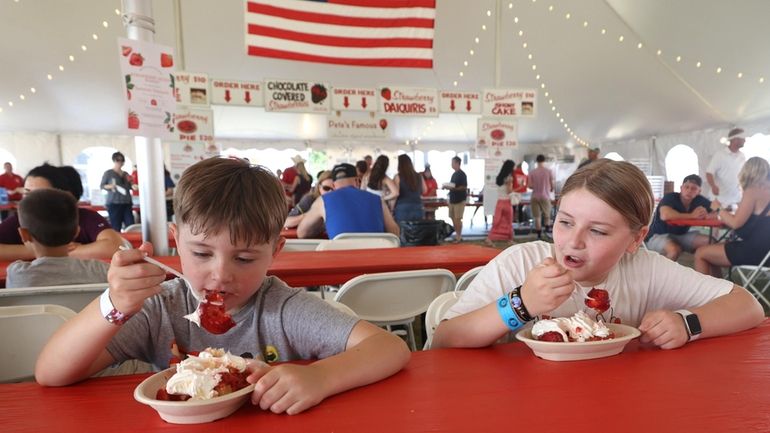 Charlize Lucarelli, right, and her brother Jacob, of Mattituck, enjoy strawberries at...