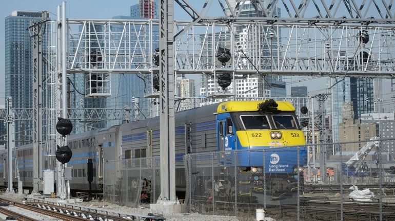 A Long Island Rail Road train passes under a signal...