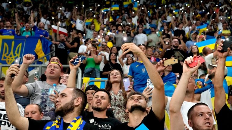 Fans of Ukraine hold smartphones with torches switched on during...