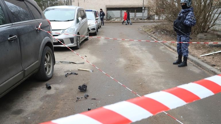 A police officer guards an area with the wreckage of...