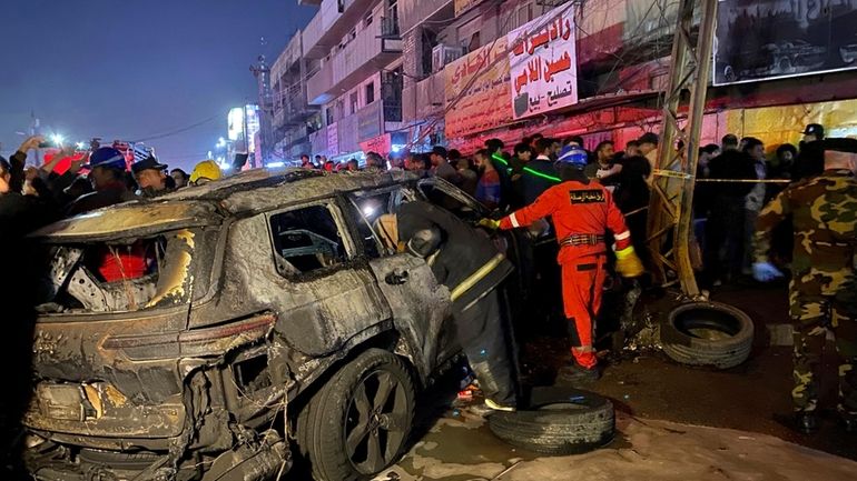 Civil defense members gather at the site of a burned...