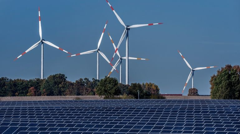 Wind turbines turn behind a solar farm in Rapshagen, Germany,...