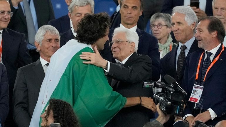 Gianmarco Tamberi, of Italy, climbs the tribune and speaks with...