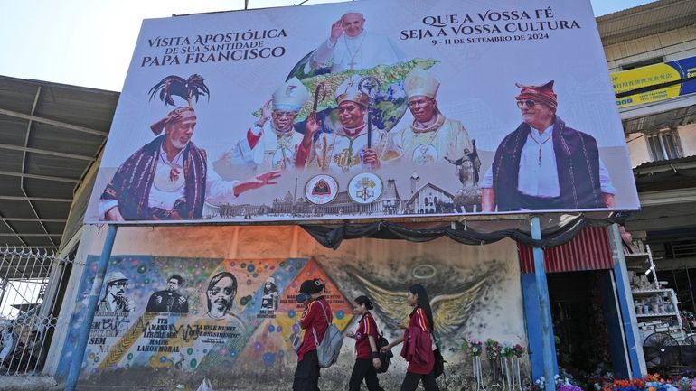 A billboard welcoming Pope Francis stands above a mural honoring...