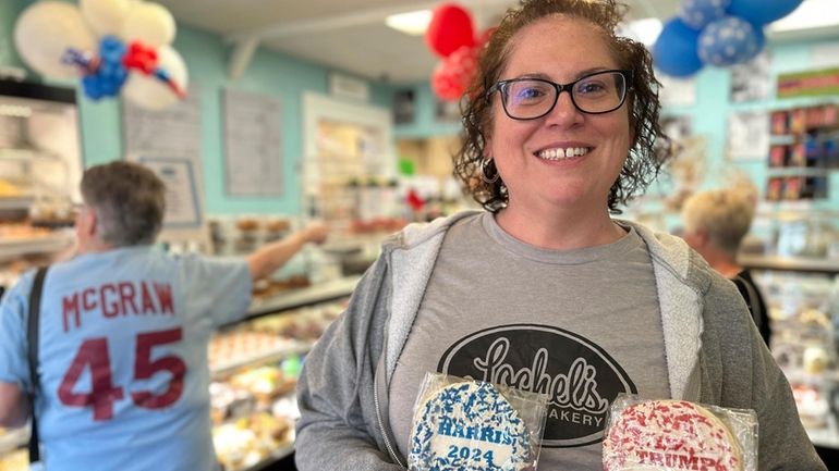 Bakery owner Kathleen Lochel holds sugar cookies, one with blue...