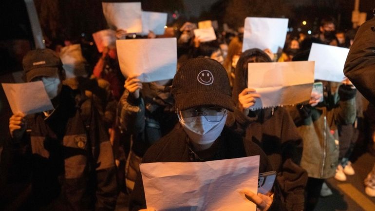 Protesters hold up blank pieces of paper and chant slogans...