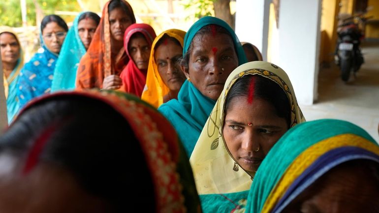 Women stand in a queue to cast their votes during...