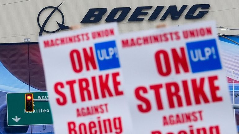 Boeing workers wave picket signs as they strike after union...