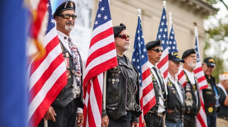 Members of the American Legion riders hold American flags during...