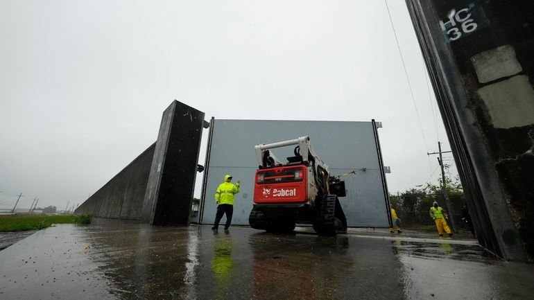 Workers from the Southeast Louisiana Flood Protection Authority-West close floodgates...