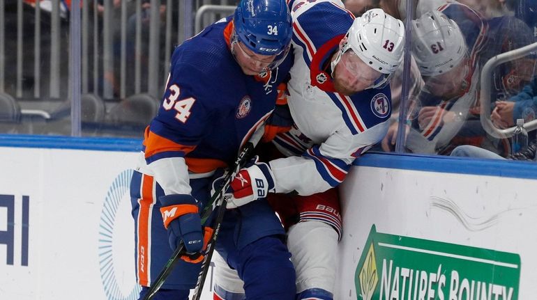 Paul LaDue of the New York Islanders checks Alexis Lafreniere...