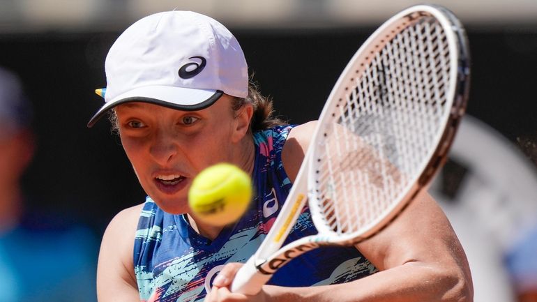 Iga Swiatek of Poland returns the ball to Victoria Azarenka...